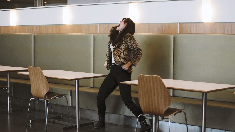Ida Haugen screams in between cafe tables while wearing a leopard print jacket.